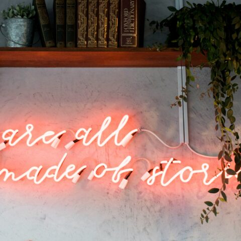 Neon lighting on a wall that says "We are all made of stories"